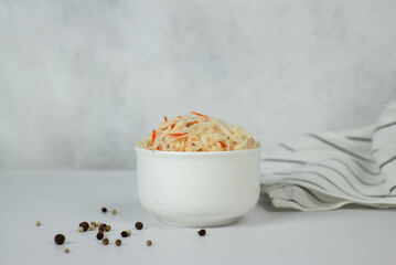Sauerkraut in a white cup on a light background.