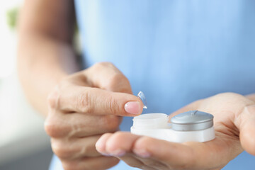 Soft contact lens with container in female hands closeup