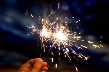 Hand holding sparkler firework firing with sky in background, concept of new year