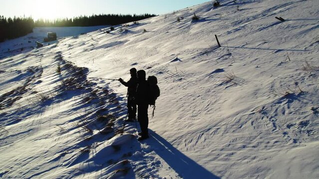 Backpackers go to the top of the hiil early in the morning. Beautiful sunrise at mountains. Winter snowy forest.