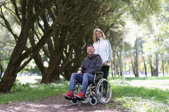 Woman on walk in park with man in wheelchair