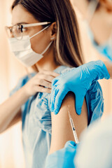 Close up of a nurse's hands injecting covid 19 vaccine in patient's shoulder. 