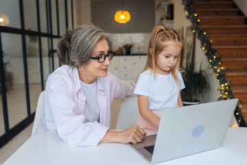 Child and granny looking at the camera with laptop