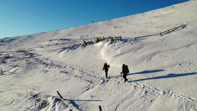 Backpackers go to the top of the hiil early in the morning. Beautiful sunrise at mountains. Winter snowy forest.