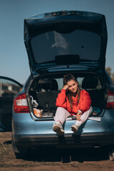 Attractive young woman resting in the trunk of a car