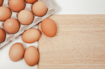The eggs on the paper tray and wooden chopping board.