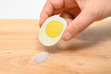 Hold a half-cut boiled egg and coat it with salt.