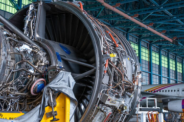 Technicians repair an aircraft gas turbine engine in the hangar. Close up of mechanics inspect an jet machine and system in aerospace industry.