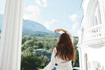 Portrait of gorgeous woman looks at a beautiful view from the balcony back view