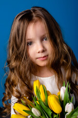 portrait of a charming smiling little girl with a bouquet of tulips in her hands. lifestyle. fresh flowers. International Women's Day. space for text. High quality photo