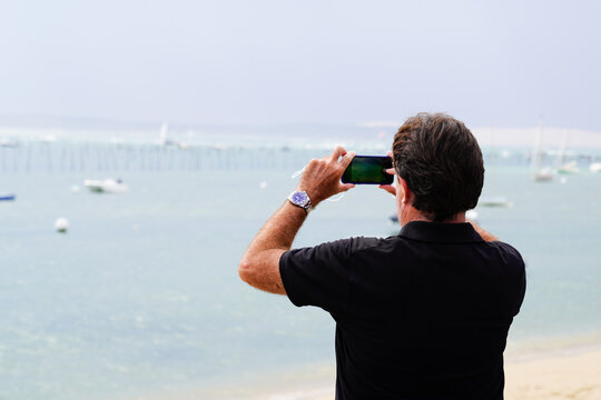 Back view of tourist young man taking picture in sea beach coast