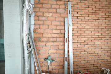 Red brick wall with water supply, new plastic pipes on concrete wall of house