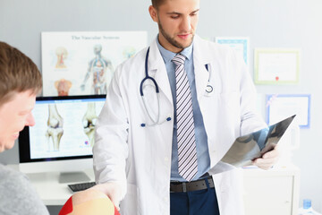 Physician wear uniform and examining patient scan, touch mans knee