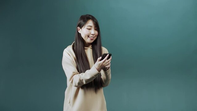 A handsome asian lady is using a phone and chatting with her friend 