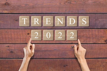 Hand flips wooden blocks and change the 'TRENDS  2022'. New trends of fashion.