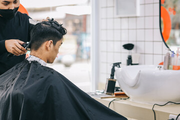 Hairdresser shaves consumer's hair with clipper