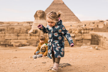 little girl and  boy plaing on background of Great Sphinx and Chephren's pyramid in Giza, Egypt