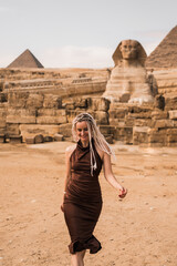 Blonde woman on background of Khafra's Pyramid and the Great Sphinx. Happy women wallking in Egypt