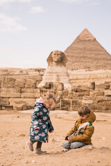 happy little girl and  boy plaing on background of Great Sphinx and Chephren's pyramid in Giza,...