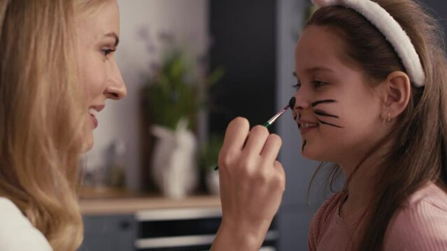 Side view of caucasian mother and daughter painting easter bunny on girl's face. Shot with RED helium camera in 8K   