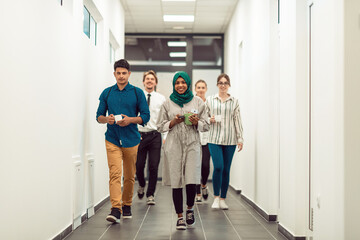 Multi-ethnic startup business team walking through the hallway of the building while coming back from a coffee break