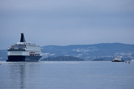 RoRo passenger and car ferry Pearl Seaways sail away from port of Oslo, Norway on sunny day with blue sky, calm water with reflection mirror and archipelago views