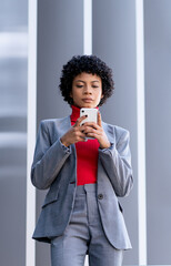 Fototapeta na wymiar Elegante mujer afroamericana utilizando el teléfono móvil en un edificio de oficinas 