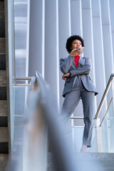 Elegante mujer afroamericana utilizando el teléfono móvil en un edificio de oficinas 