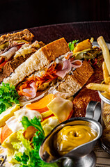 Dinner table with french fries, vegetables, sauces, salad and sandwich 