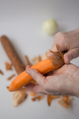 hands of an elderly woman peel vegetables carrots and onions with a knife