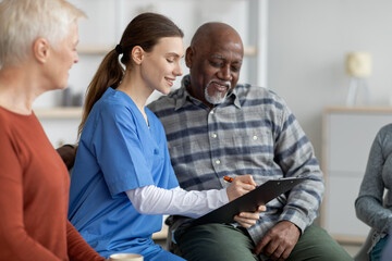 Supportive nursing home attendant helping senior black man filling papers