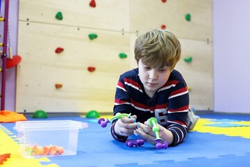 child boy on the floor of the children's center for the development of special children playing a chain of viruses lifestyle concept feature of the time