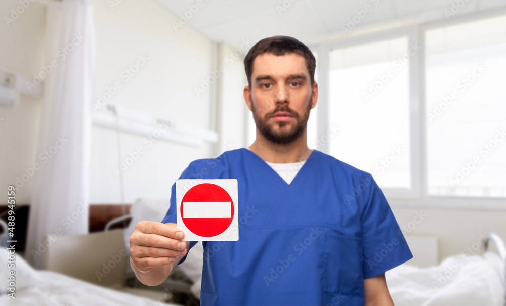 Poster healthcare, profession and medicine concept - male doctor in blue uniform showing stop sign over hospital ward background