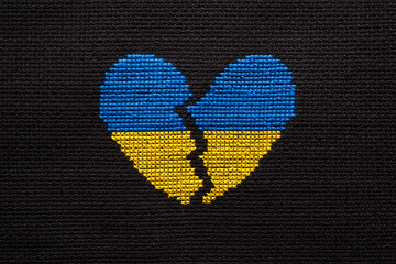 Broken heart the color of the flag of Ukraine embroidered on a black background.