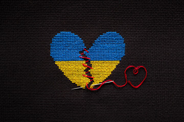 Broken heart the color of the flag of Ukraine embroidered on a black background.