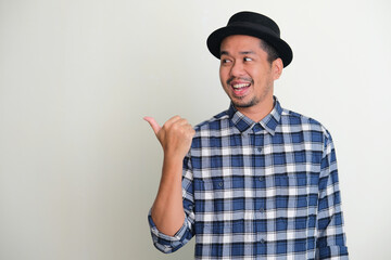 Adult Asian man looking and pointing to the right with happy expression