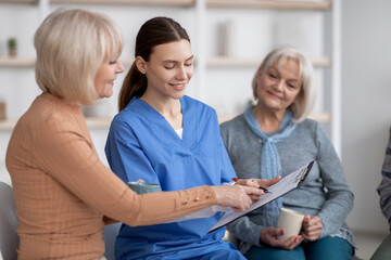 Pretty young nurse questioning senior ladies at nursing home