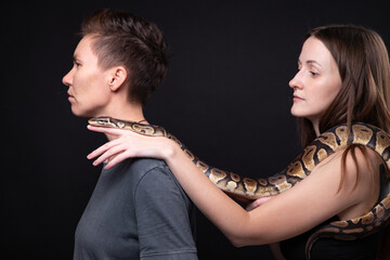 Photo of two women with python on shoulders in profile