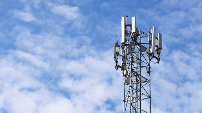 4G and 5G Cellular Base Station. Base Transceiver Station (BSC) Radio transceiver with cell phone in cellular wireless communication system on metal towers on cloudy sky background with copy space.