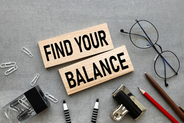 Find your balance text on wooden blocks on a gray background near glasses and stationery