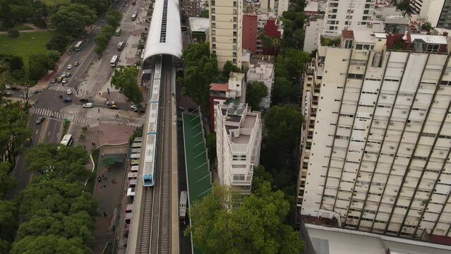 Train arriving at Barrancas of Belgrano station in Buenos Aires. Aerial top-down forward