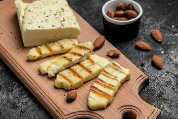 Fototapeta na wymiar Grilled Halloumi cheese with mint and almonds on a wooden board, Cyprus squeaky cheese