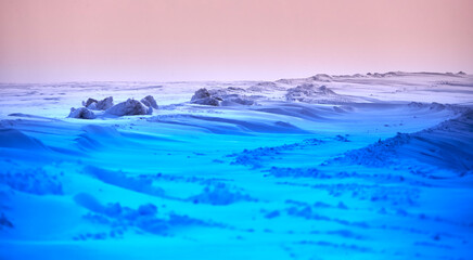 Obraz premium Field covered with blue and orange snow. Ice hummocks and wind.
