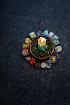 Rune stones with symbols and candle on abstract black background. minerals pebble with rune symbols for fortune telling, prediction destiny. ancient witch and shaman magic ritual. top view