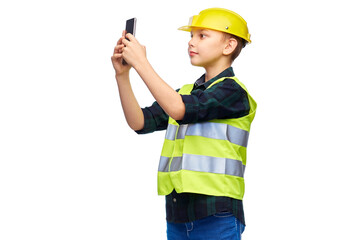 building, construction and profession concept - happy smiling little boy in protective helmet and safety vest taking selfie with smartphone over white background