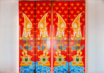 Vintage deity painting Thai design on ancient wooden doors. The door entrance of Buddhist temple at Wat Nong Waeng in Khon Kaen province, Thailand.