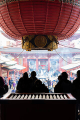 Silhouette of pilgrims praying in front of a saisen-bako or offertory box. The tourists are in Hondo, the main hall of Senso-ji Temple.
