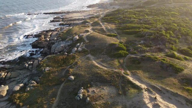 A couple walks the rocky beach of Puta del Diablo Uruguay.