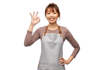 cooking, culinary and people concept - happy smiling female chef or waitress in apron showing ok gesture over white background
