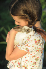 Girl hugging baby rabbit outdoors